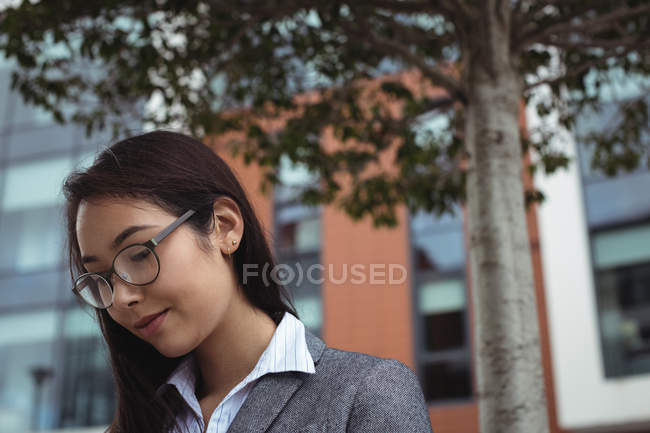 Close-up de mulher de negócios sorridente em óculos de pé na rua da cidade — Fotografia de Stock