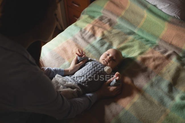 Mère jouant avec bébé mignon dans la chambre à coucher à la maison — Photo de stock