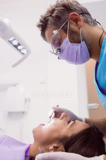 Dentista esaminando paziente femminile con strumenti presso la clinica dentale — Foto stock