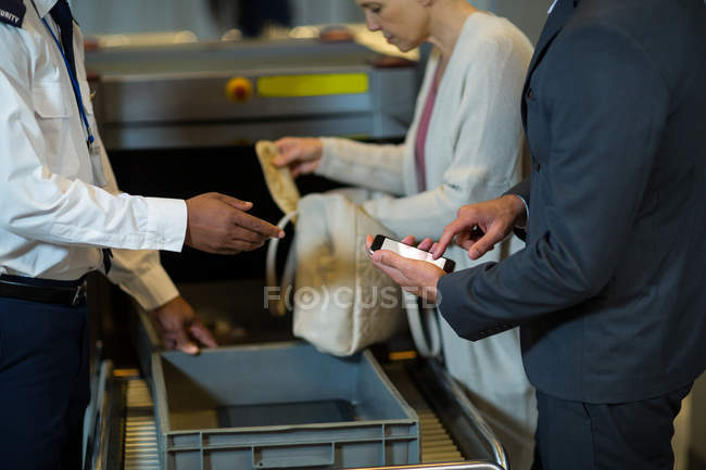 Oficial de seguridad del aeropuerto revisando bolsa de viajero en el aeropuerto - foto de stock