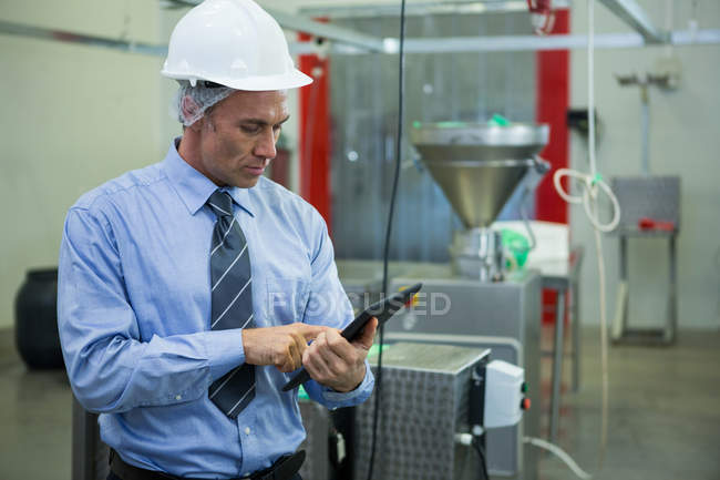 Technicien attentif utilisant une tablette numérique à l'usine de viande — Photo de stock