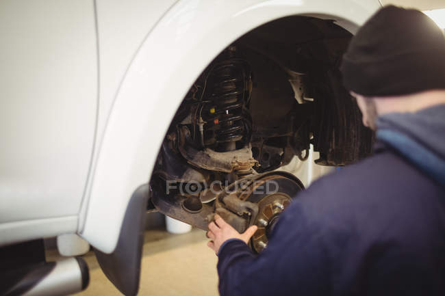 Mecânico examinando um freio de disco de roda de carro na garagem de reparo — Fotografia de Stock