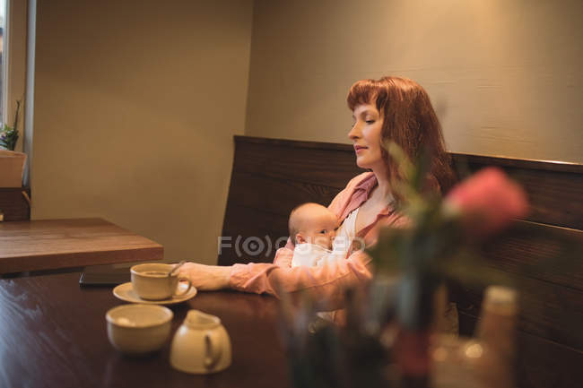 Mutter mit Baby benutzt Handy in Café — Stockfoto