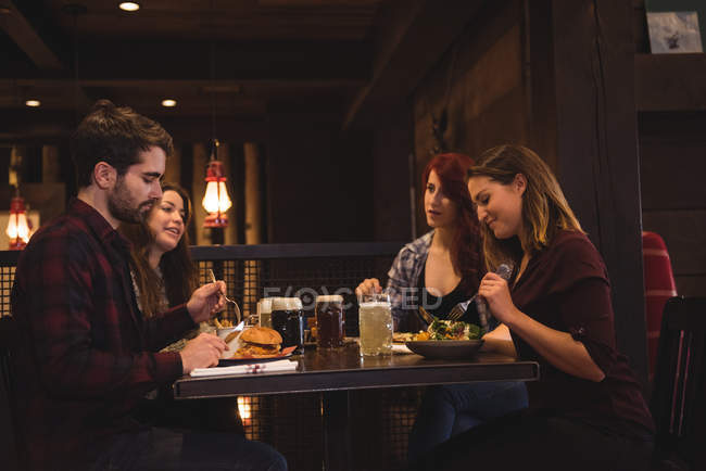 Amici che parlano mentre si godono il cibo nel bar — Foto stock