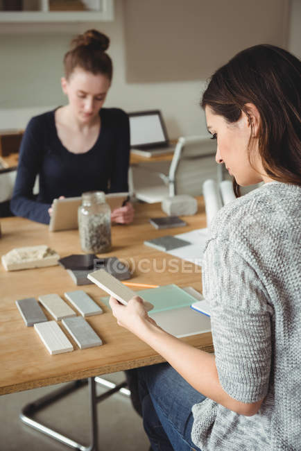 Geschäftsführer schaut sich Steinplatte an, während Kollege im Büro digitales Tablet nutzt — Stockfoto