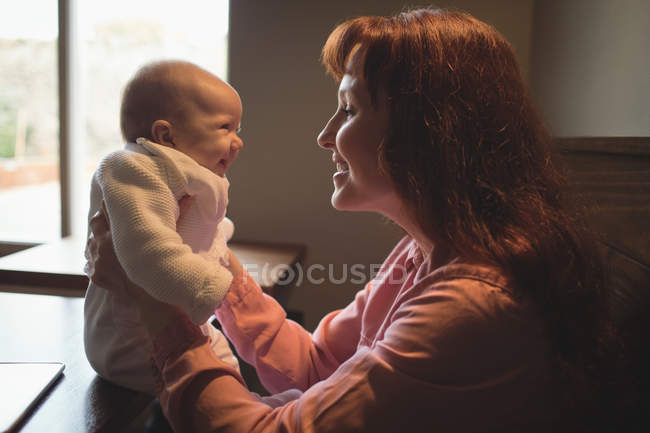 Mãe feliz brincando com bebê dentro de casa — Fotografia de Stock