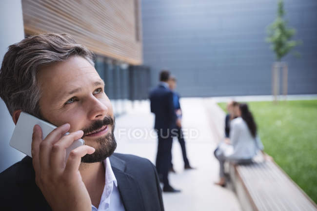 Uomo d'affari che parla sul cellulare fuori dall'edificio degli uffici — Foto stock