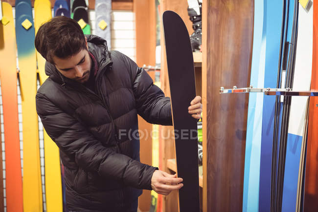 Hombre guapo seleccionando esquí en una tienda - foto de stock