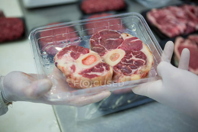 Carniceros empacan carne cruda en bandeja de plástico en fábrica de carne - foto de stock