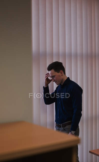 Uomo sconvolto in piedi con mano sulla fronte in ufficio — Foto stock