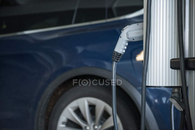 Close-up de carregamento de carro com carregador de carro elétrico na estação de carregamento — Fotografia de Stock