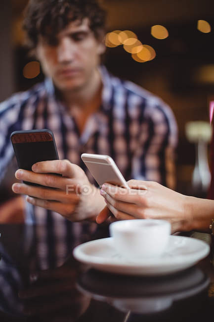 Couple utilisant des téléphones mobiles dans le restaurant — Photo de stock