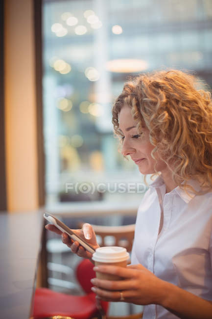 Блондинка бізнес-леді, використовуючи смартфон за лічильником в кафетерії — стокове фото