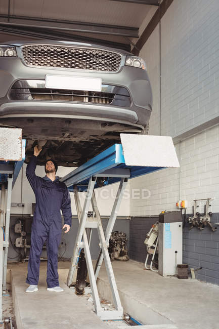 Mécanicien examinant une voiture au garage de réparation — Photo de stock