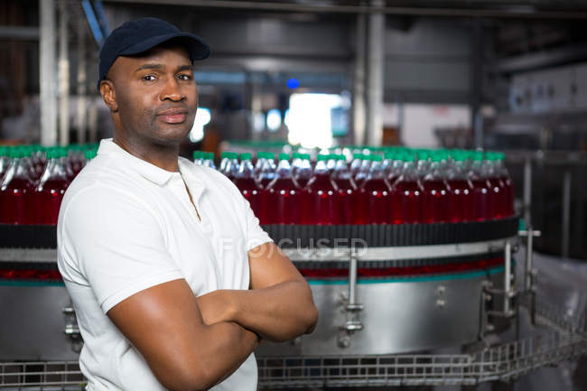 Portrait of confident male employee with arms crossed standing in factory — Stock Photo