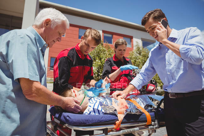 Paramédicos examinando menino ferido na rua — Fotografia de Stock