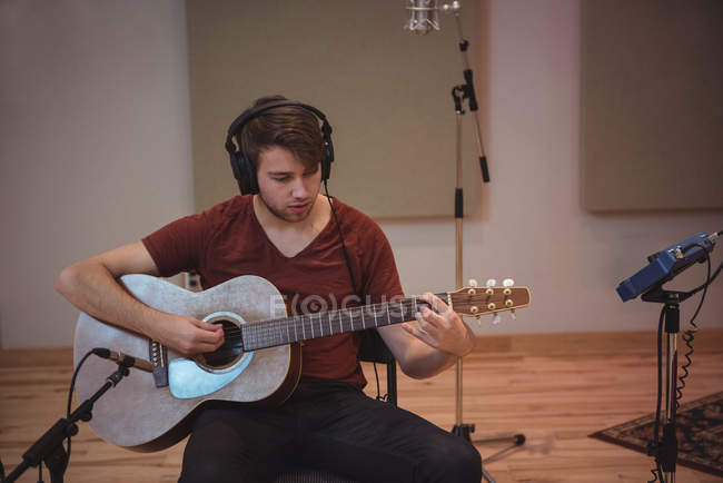 Homme jouant une guitare dans un studio de musique — Photo de stock