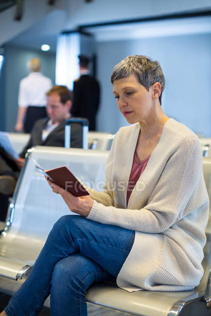 Frau schaut auf Pass im Wartebereich am Flughafen-Terminal — Stockfoto