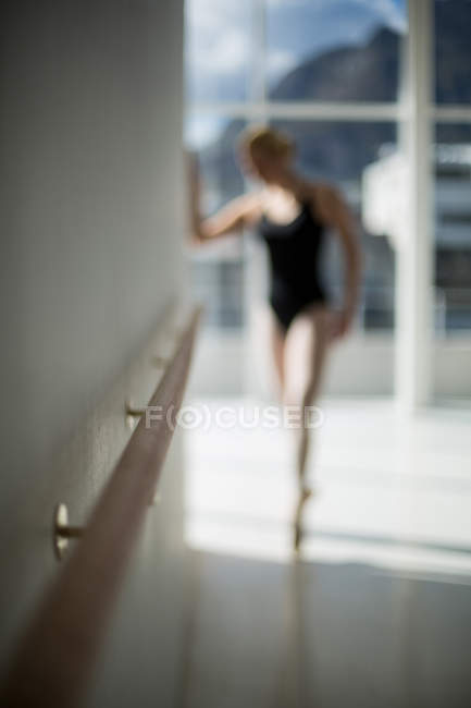 Bailarina estirándose en una pared mientras practica danza de ballet en el estudio - foto de stock