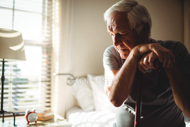 Продуманий старший чоловік з своїй тростиною в спальні в домашніх умовах — стокове фото