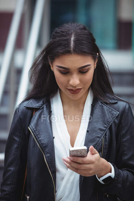 Жінка, використовуючи мобільний телефон за межами офісних приміщень — стокове фото