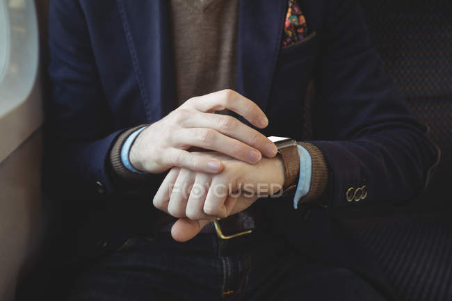 Mid-section of businessman using smartwatch while travelling in train — Stock Photo