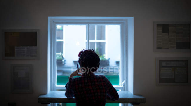 Vista trasera de la mujer mirando a través de la ventana en la cafetería - foto de stock