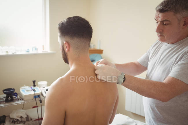 Fisioterapeuta realizando agujas secas en el hombro del paciente en la clínica - foto de stock