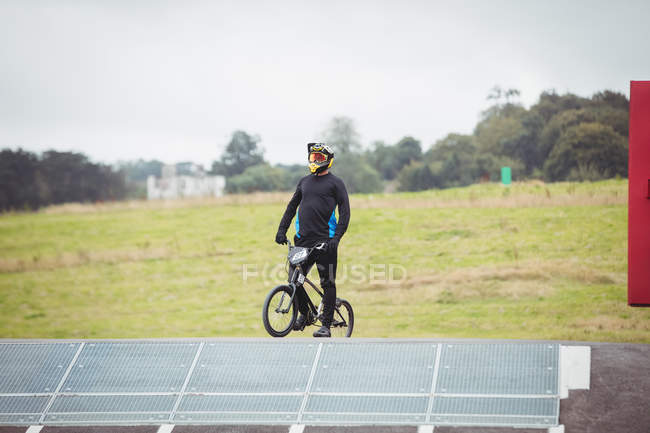 Велосипедист, стоящий на велосипеде BMX на старте пандуса в скейтпарке — стоковое фото