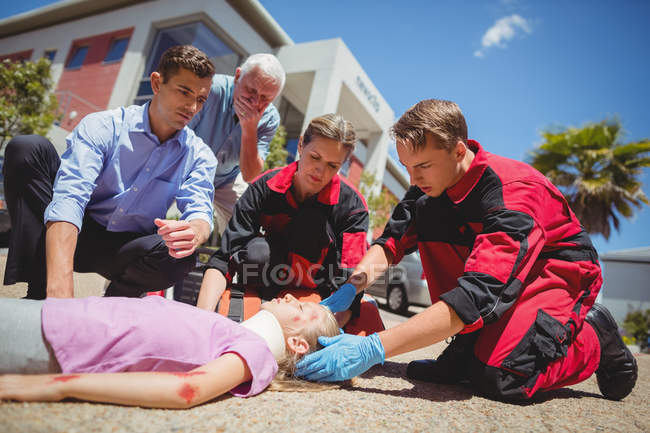 Парамедики осматривают раненую девушку на улице — стоковое фото