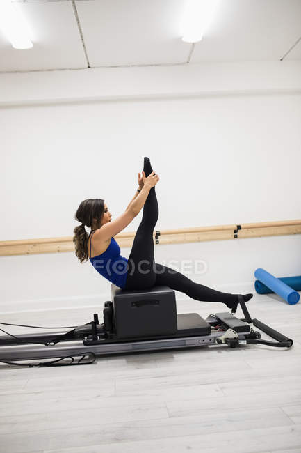 Mujer adulta haciendo ejercicio sobre reformador en el gimnasio - foto de stock