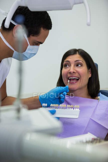 Дантист осматривает пациентку с оттенками зубов в стоматологической клинике — стоковое фото