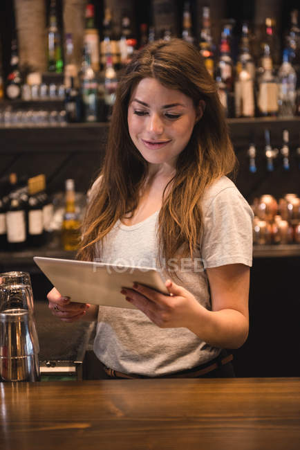 Female bartender using digital tablet at bar counter — Stock Photo