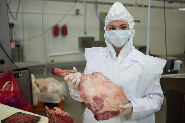 Retrato de açougueiro fêmea segurando carne na fábrica de carne — Fotografia de Stock
