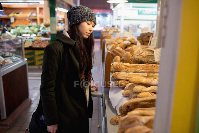 Жінка дивиться на різні хліби на лічильнику в супермаркеті — стокове фото