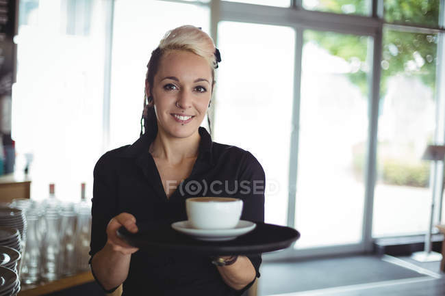 Портрет офіціантки, що стоїть з чашкою кави в кафе — стокове фото