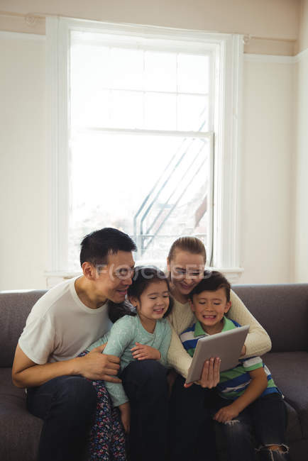 Famille heureuse en utilisant une tablette numérique dans le salon — Photo de stock