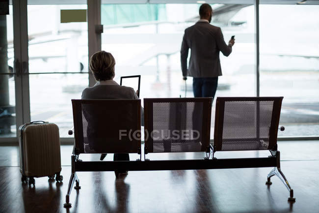 Vista trasera de la gente de negocios en la zona de espera en la terminal del aeropuerto - foto de stock