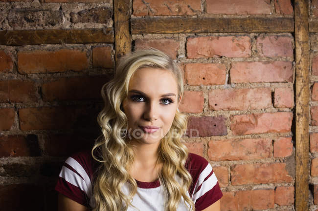 Beautiful woman standing against brick wall — Stock Photo