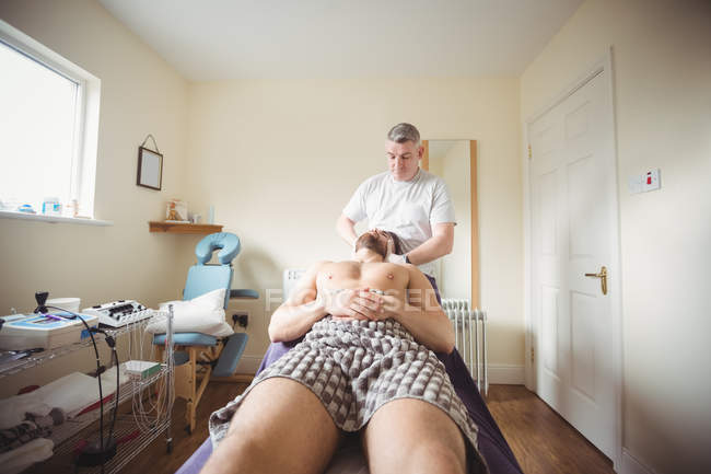 Fisioterapeuta examinando pescoço de paciente do sexo masculino na clínica — Fotografia de Stock
