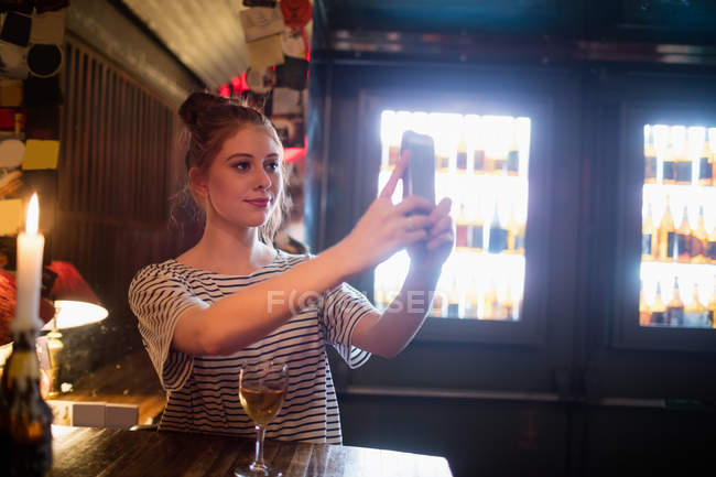 Schöne Frau macht Selfie vom Handy in Bar — Stockfoto