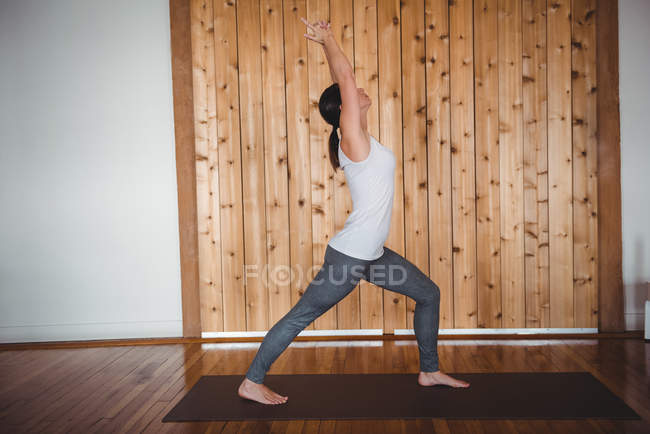 Mujer practicando yoga en gimnasio, vista lateral - foto de stock