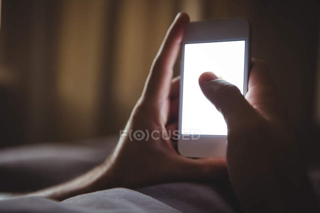 Крупним планом чоловічі руки, використовуючи мобільний телефон в спальні — стокове фото