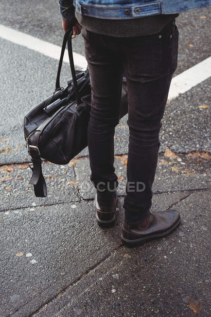 Нижняя часть человека с сумочкой стоит на улице — стоковое фото