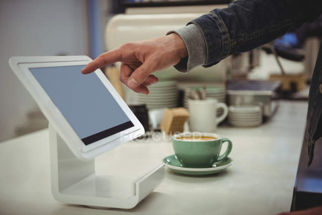 Mão do homem usando tablet digital mantida em stand no café — Fotografia de Stock
