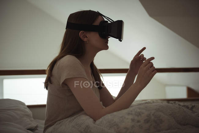 Donna che utilizza cuffie realtà virtuale a letto a casa — Foto stock
