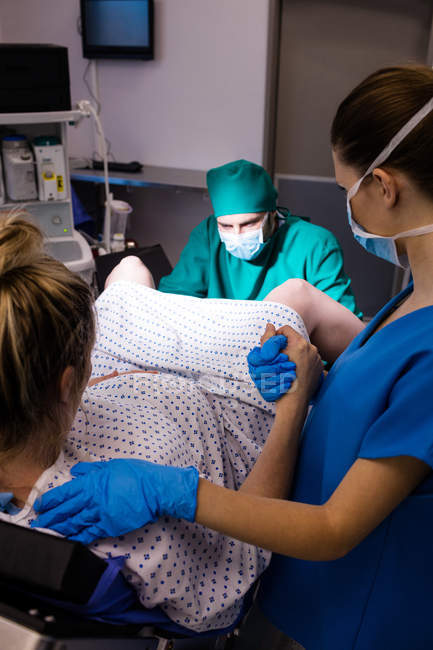 Medical team examining pregnant woman during delivery in operating room — Stock Photo
