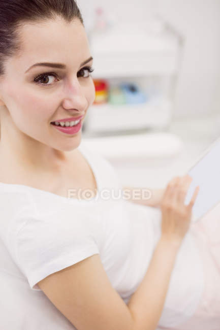Primer plano de la hermosa mujer usando tableta digital en la silla de la clínica - foto de stock