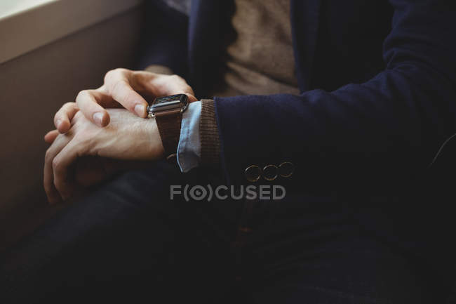 Mid-section of businessman checking time on watch while travelling in train — Stock Photo