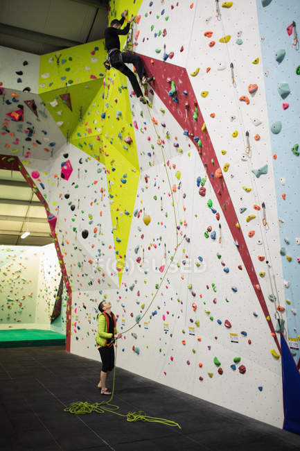 Man practicing rock climbing on artificial climbing wall in gym — Stock Photo